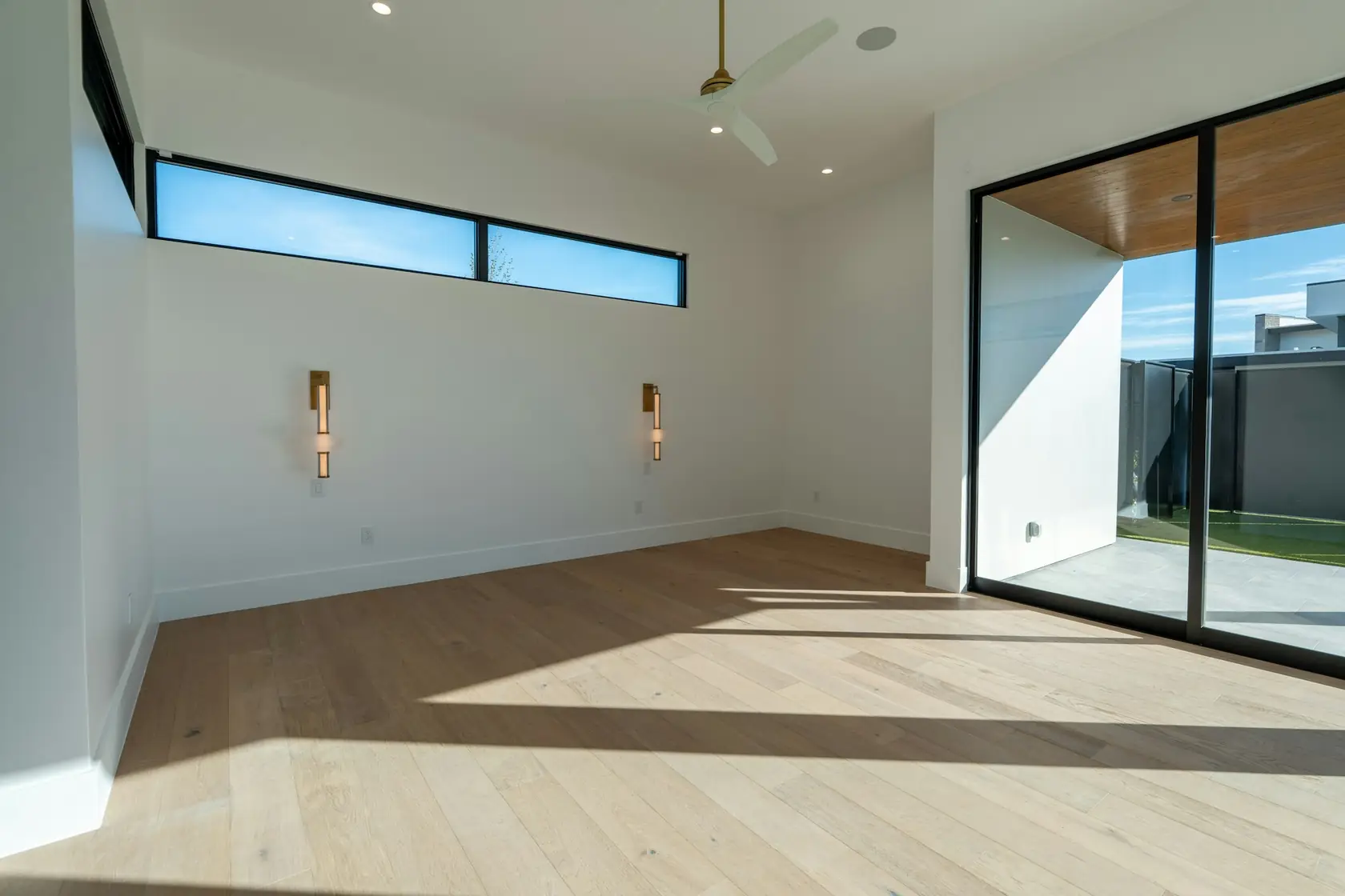 Pièce vide rénovée, parquet clair et baie vitrée coulissante